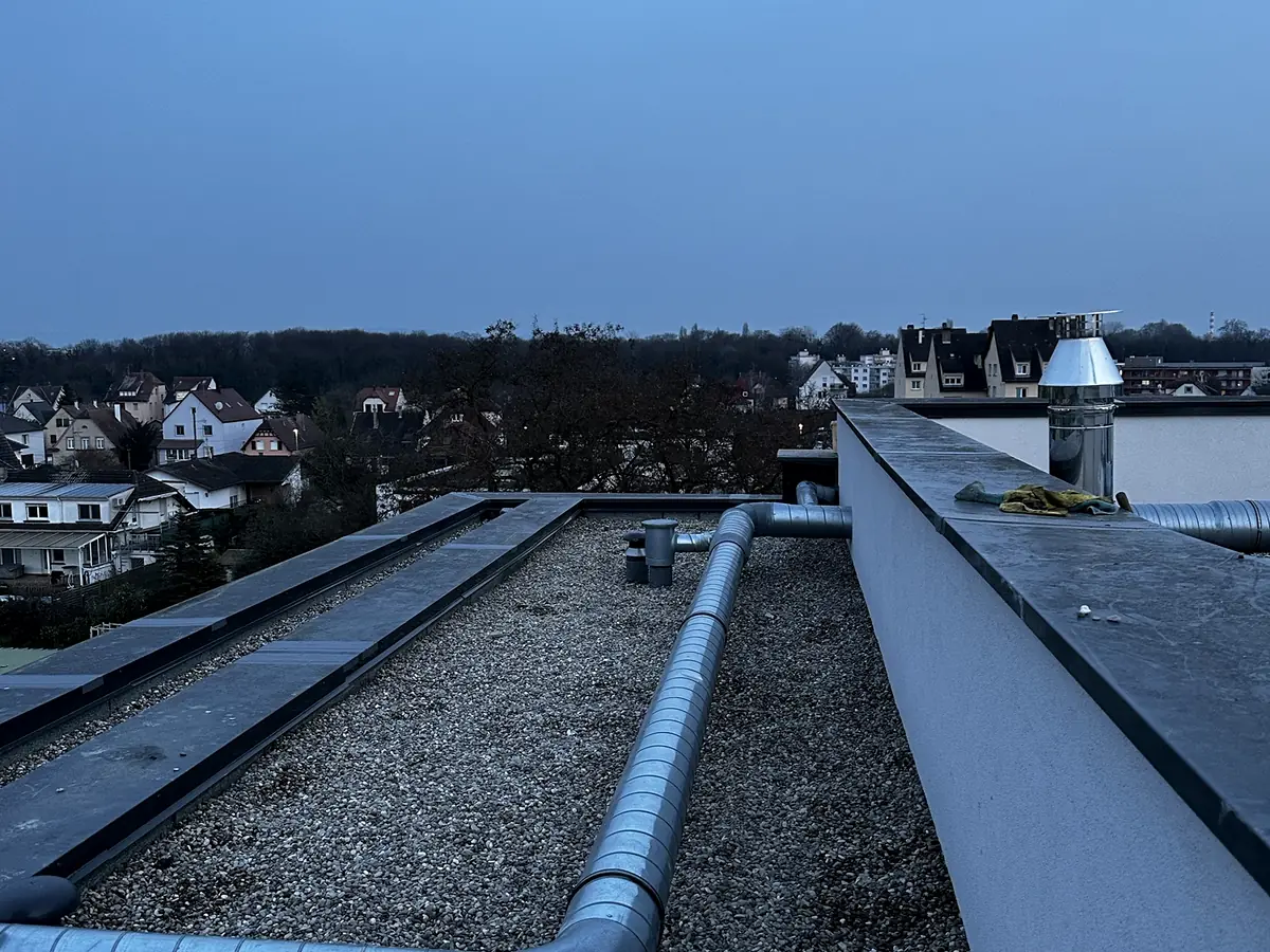 Toiture-terrasse gravillonnée au crépuscule, sorties de ventilation